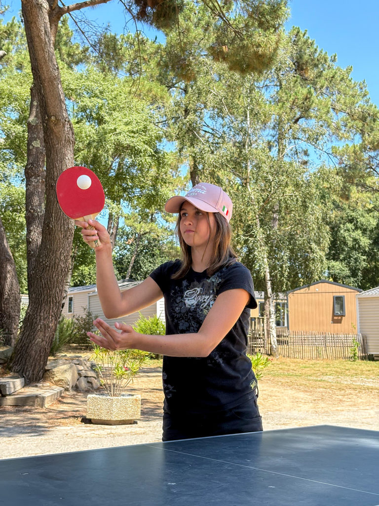 Jeune fille qui joue au tennis de table au camping en Bretagne