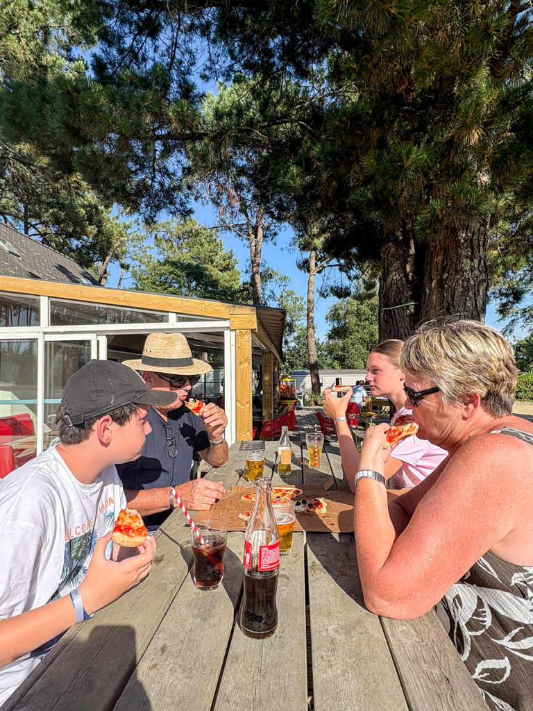 Famille qui mange une pizza en terrasse de restaurant du camping Le Fort Espagnol